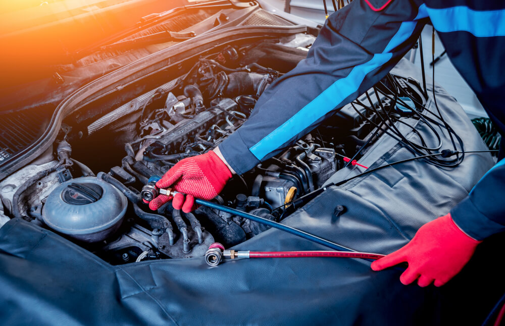 Kfz-Mechaniker mit roten Handschuhen repariert die Klimaanlage